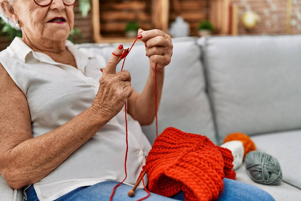 Vanhempi harmaa tukka nainen ompelu käyttäen kaistaa ja neulaa kotona - Valokuva, kuva