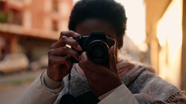 Молода афроамериканська жінка, яка користується професійною камерою на вулиці. - Фото, зображення