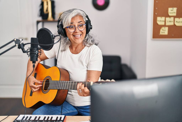 Mujer de mediana edad músico cantando canción tocando guitarra clásica en el estudio de música - Foto, imagen