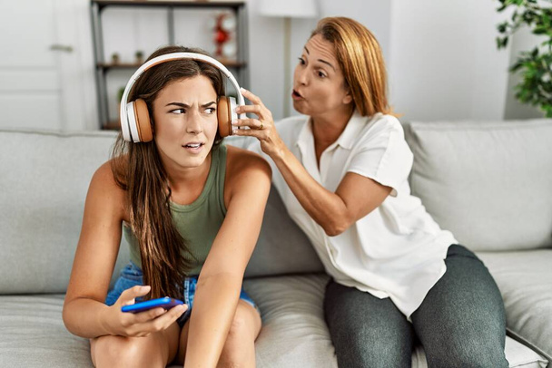 Anne ve kızı evde tartışırken ve müzik dinlerken mutsuz oluyorlar. - Fotoğraf, Görsel