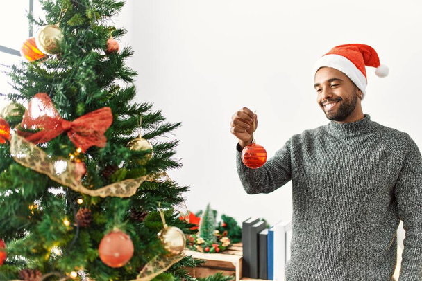 Young african american man smiling happy holding christmas ball at home. - Photo, Image