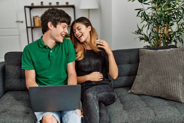 若いですcaucasianカップル笑顔幸せな使用ノートパソコンにホーム. - 写真・画像