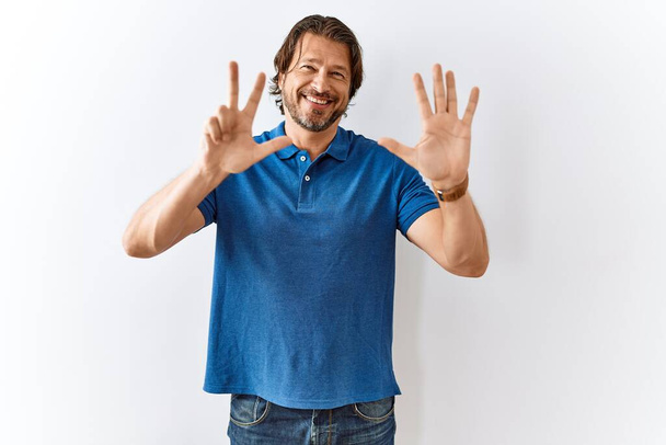 Handsome middle age man standing together over isolated background showing and pointing up with fingers number eight while smiling confident and happy.  - Photo, Image