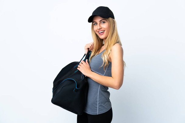 Mladá blondýna žena drží sportovní tašku přes izolované bílé pozadí s úsměvem hodně - Fotografie, Obrázek