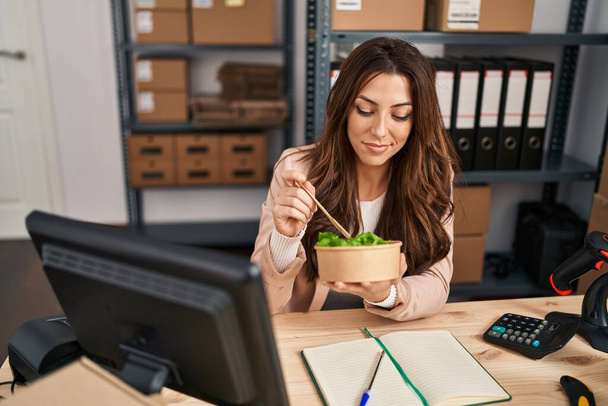 若いヒスパニック系の女性は、オフィスでサラダを食べるビジネスワーカーをeコマース - 写真・画像
