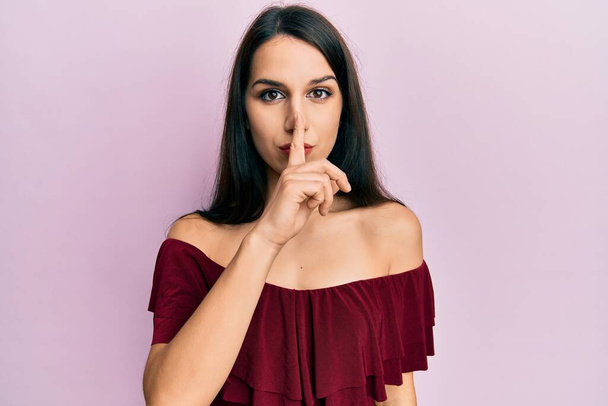 Young hispanic woman wearing casual clothes asking to be quiet with finger on lips. silence and secret concept.  - Fotó, kép