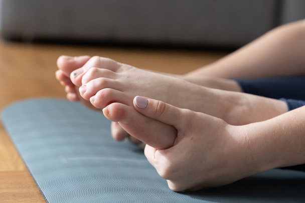 Closeup view of hands of dancer holding feet while stretching - Photo, image