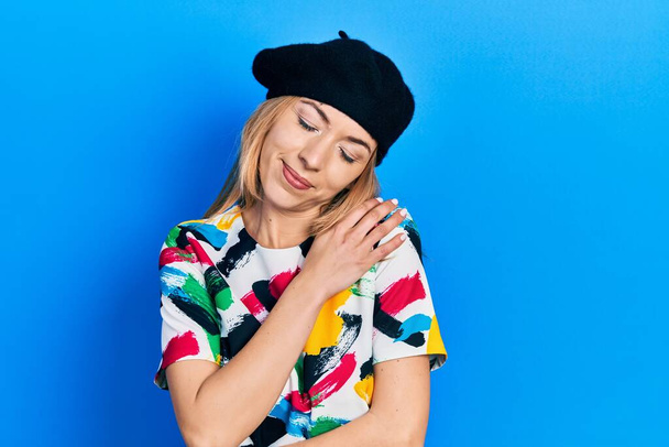 Young caucasian woman wearing french look with beret hugging oneself happy and positive, smiling confident. self love and self care  - Photo, image