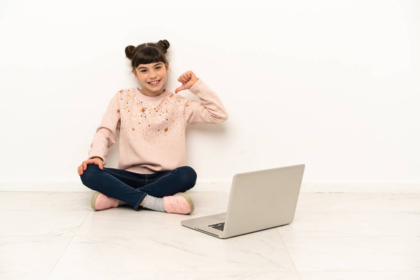 Little girl with a laptop sitting on the floor proud and self-satisfied - Photo, Image