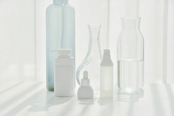 Kozmetikai palack tartályok és kristálytiszta üvegáruk, Minimális bőrápolási koncepció fény- és árnyékvisszaverő hatással, Tisztaság cosmeceutical beauty care. - Fotó, kép