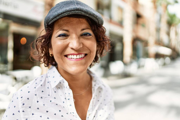 Mujer latina de mediana edad sonriendo feliz de pie en la ciudad. - Foto, Imagen