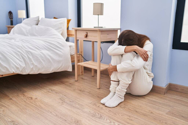 Молода жінка сидить на підлозі плаче в спальні
 - Фото, зображення