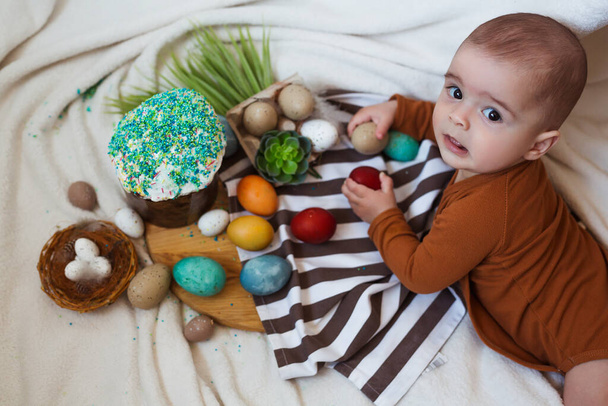 Feliz Páscoa. Bebê bonito e feliz brincando com ovos de Páscoa e bolo em casa. - Foto, Imagem