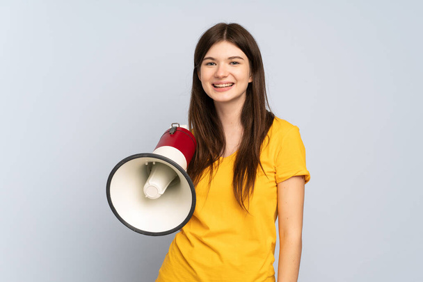 Young Ukrainian girl isolated on white background holding a megaphone and smiling a lot - Photo, image