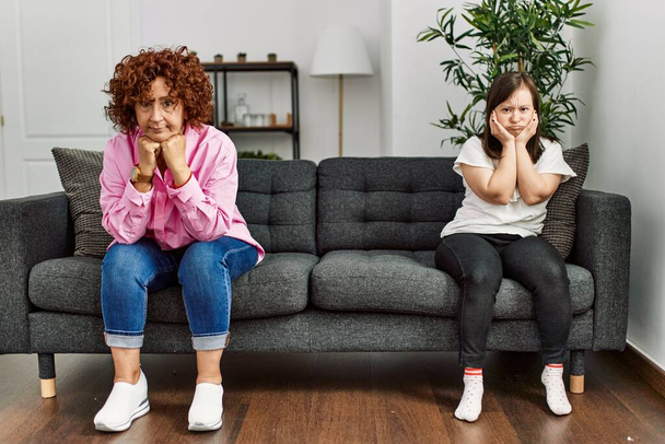 Olgun anne ve Down sendromlu kız evde tartıştıktan sonra üzgün ve kızgın görünüyorlar. - Fotoğraf, Görsel