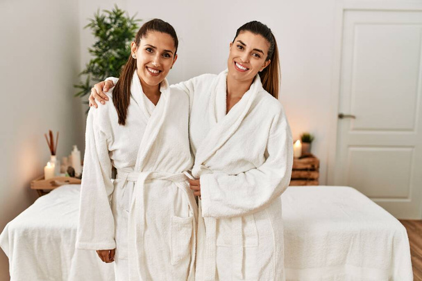Дві жінки в халаті обнімаються, стоячи в центрі краси
 - Фото, зображення