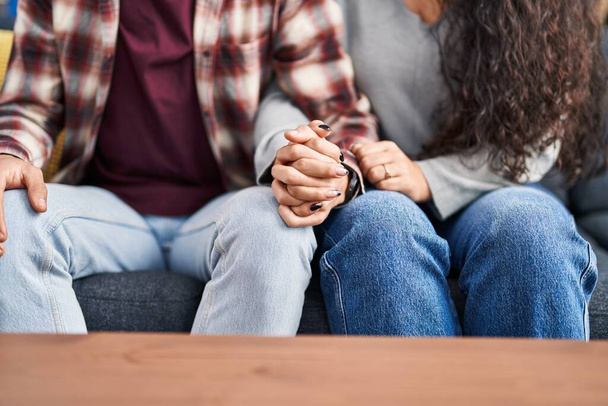 Man and woman couple sitting on sofa with hands together at home - Foto, Imagem