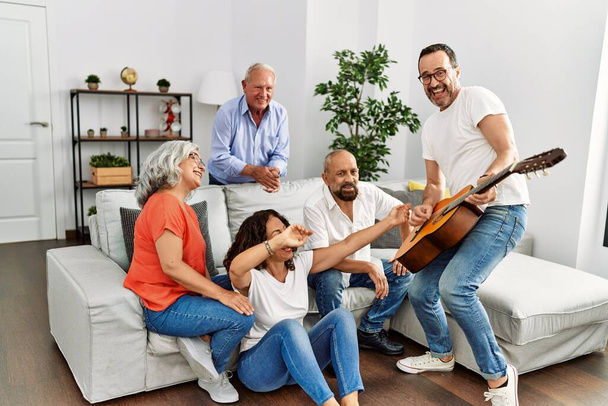 Bir grup orta yaşlı arkadaş evdeki kanepede oturup klasik gitar çalıyorlar.. - Fotoğraf, Görsel