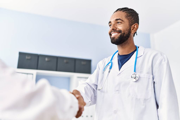 Homme et femme portant l'uniforme de médecin souriant confiant serrer la main à la clinique - Photo, image