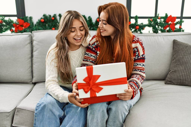 Donna coppia disimballaggio regalo seduto da decorazioni natalizie a casa - Foto, immagini
