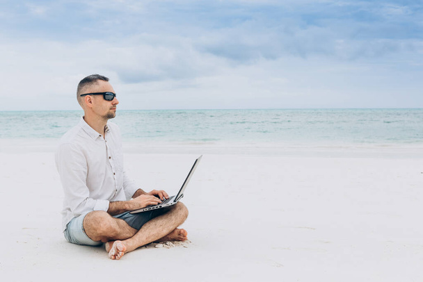 Man hands typing text on laptop computer in front blue sea on thw beach. Concept remote work, freelance. - Foto, immagini