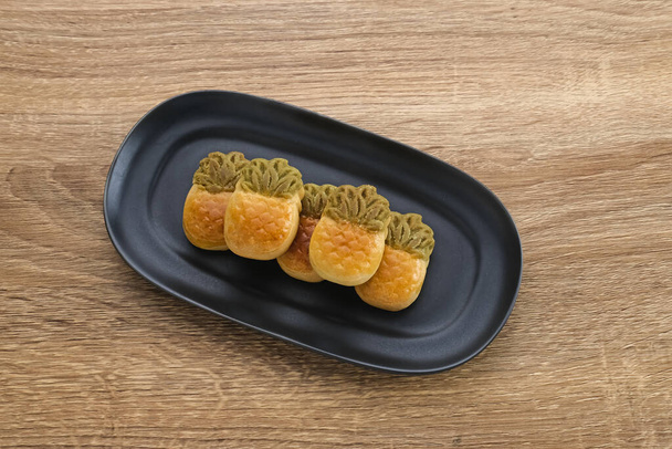 Nastar Cookies, tajvani ananász alakú lekvárral töltött sütik. Fekete tányérban tálalva - Fotó, kép