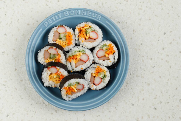 Gimbap or Kimbap, Korean Roll Rice with Nori Laver, Egg, Crab Stick, carrot, and Cucumber. Top View on Ceramic Plate, Copy Space - Photo, Image