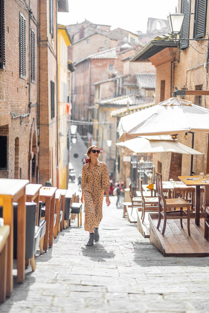 Sylish woman walks on narrow and cozy street in old town of Siena city - Φωτογραφία, εικόνα