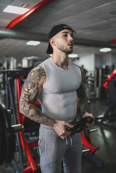 handsome young man in sportswear posing in gym - Фото, изображение