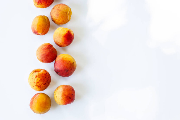Ripe, tasty and juicy apricots on a white background with place for text, copy space. Seasonal fruits. View from above - Φωτογραφία, εικόνα