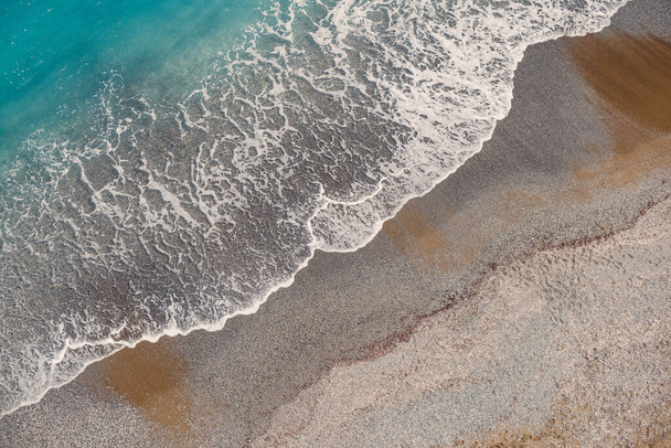 Vista superior de la orilla del mar con agua azul y una playa de arena. Vista aérea del mar de la Tierra Media con costa. Hermoso mar tropical en temporada de verano, disparado desde un dron - Foto, imagen