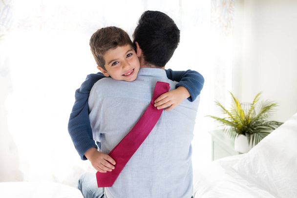 Syn przytulający ojca z krawatem na rękach - Zdjęcie, obraz