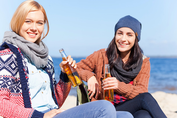 Young women holding beer bottles on the beach - Photo, image