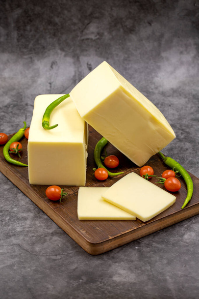 Τυρί Cheddar ή κασκαβάλ σε σκούρο φόντο. Τυρί φέτες στον πίνακα σερβιρίσματος - Φωτογραφία, εικόνα