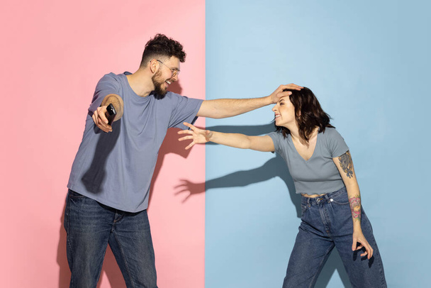 Portrait of young emotional man and girl isolated on blue and pink trendy color background. Human emotions concept - Fotoğraf, Görsel