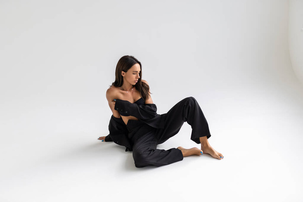 Portrait of a brunette woman in a business suit on the floor - Фото, изображение