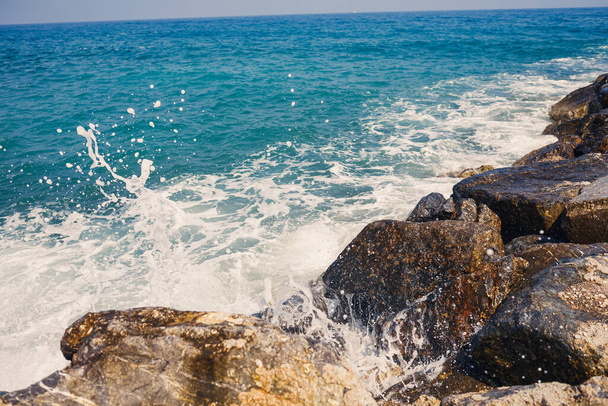 海の水は岩に打ち勝ち泡で波を作ります - 写真・画像