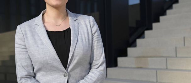 businesswoman standing with arms crossed against building background - Foto, Bild
