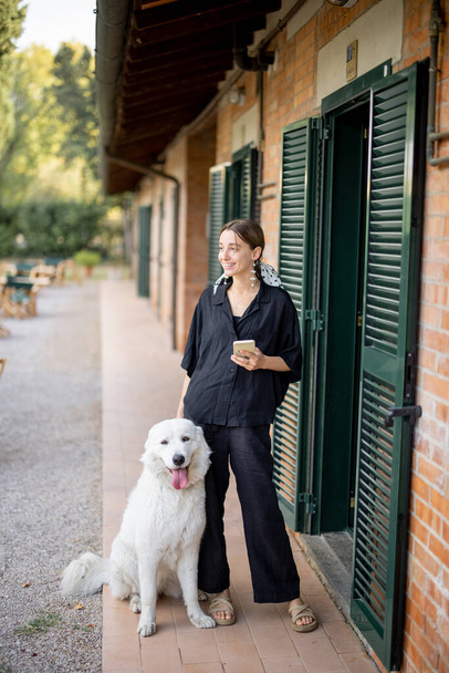Woman standing with dog and looking away near entrance to hotel room - Foto, immagini