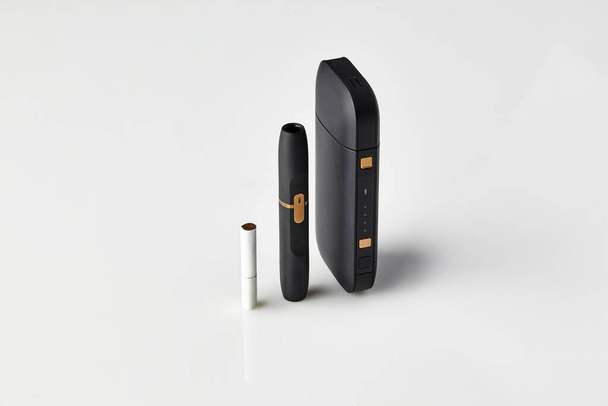Nová generace černé elektronické cigarety, baterie a jeden tepelný pás izolované na bílém. Technologický tabákový systém vytápění. Nová technologie. Zavřít - Fotografie, Obrázek