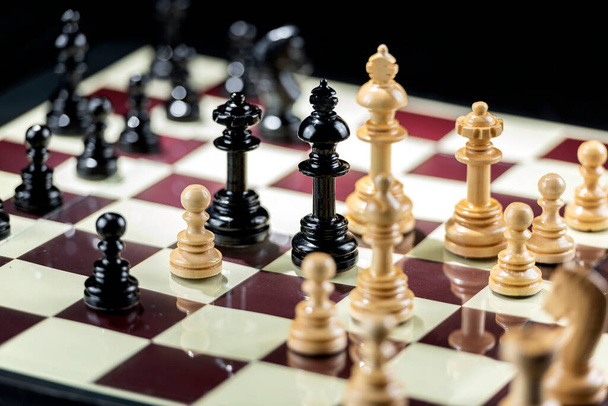 Chess pieces on the chessboard with black background - Foto, imagen