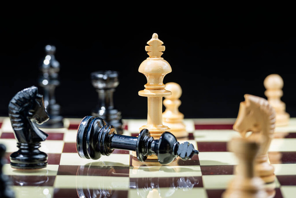 Chess pieces on the chessboard with black background - Foto, imagen