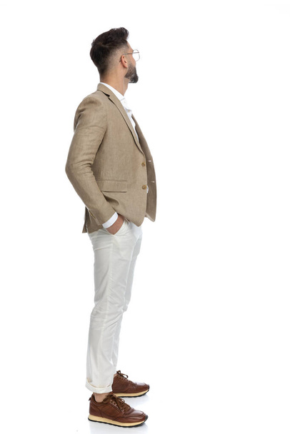 side view of an attractive businessman waiting in line with his hands in pocket and looking away  - Photo, image
