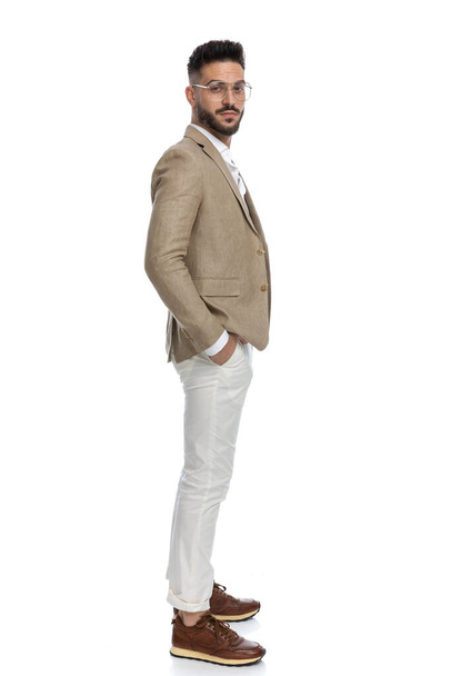 side view of a young businessman waiting in line and looking at the camera against white background - Photo, Image