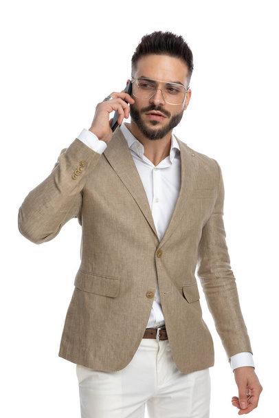 привабливий бізнесмен глибоко розмовляє по телефону, дивлячись на білий фон
 - Фото, зображення