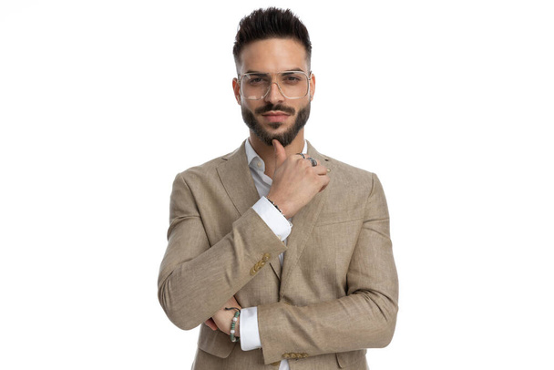attraktiver Geschäftsmann mit sinnlichem Blick im Gesicht, verschränkten Armen und posiert vor weißem Hintergrund - Foto, Bild