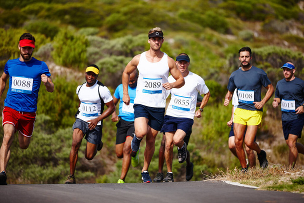 Das Tempo vorgeben. Aufnahme einer Gruppe junger Männer, die einen Marathon laufen. - Foto, Bild