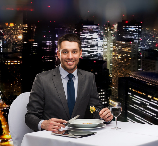 smiling man with tablet pc eating main course - Foto, Imagen