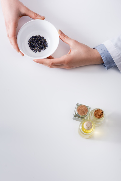 top view of woman holding bowl with dried lavender while making cosmetics - Photo, Image