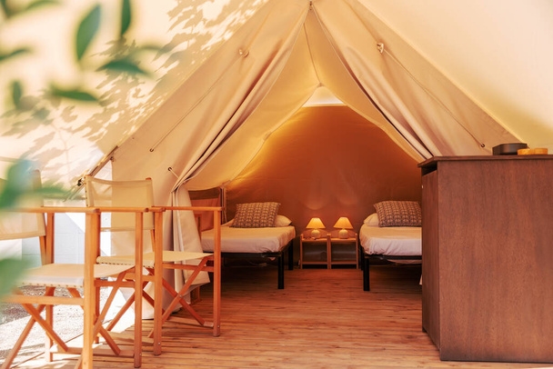 Яркая палатка с уютным интерьером в солнечный день. Люксовый кемпинг-шатер для летнего отдыха под открытым небом - Фото, изображение